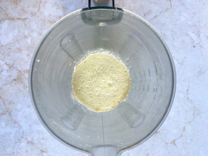 Um liquidificador contendo a mistura de leite, manteiga, ovos, açúcar, sal, queijo ralado e orégano.