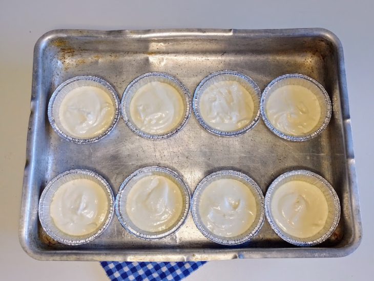 Uma assadeira contendo forminhas com a massa crua de pão de queijo.