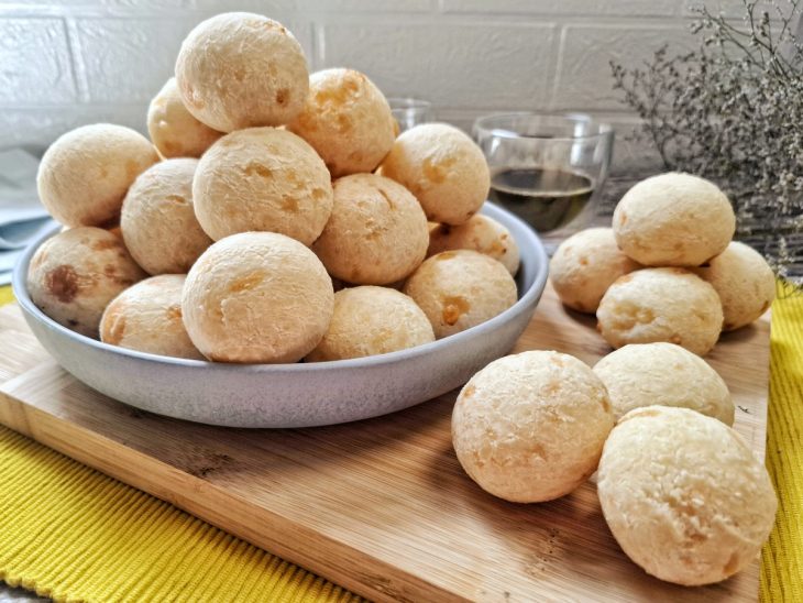 Um prato e tábua com pão de queijo mineiro.