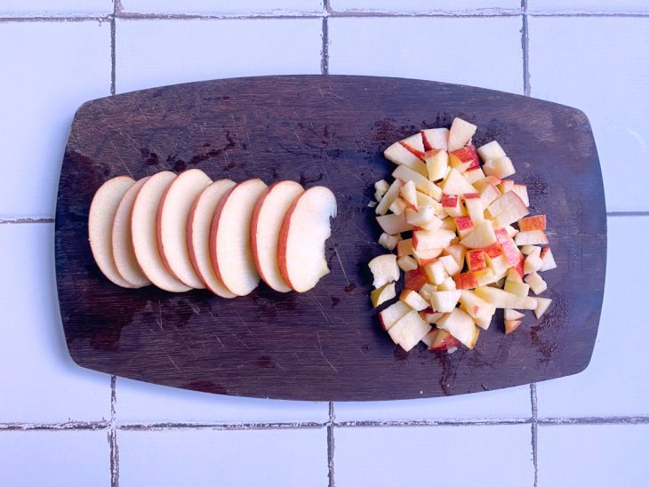 Uma tábua contendo maçã em cubos e fatias.