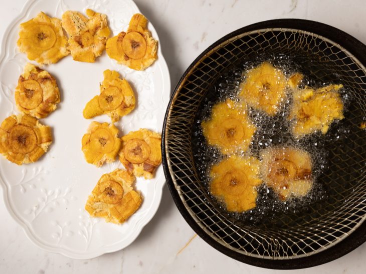 Patacones fritos em uma panela com óleo.