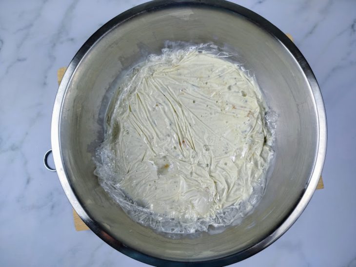 Uma tigela com patê de gorgonzola com damasco coberto com plástico-filme.