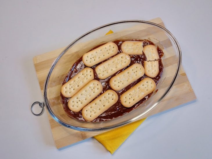Um refratário forrado com creme de chocolate e coberto com bolachas.
