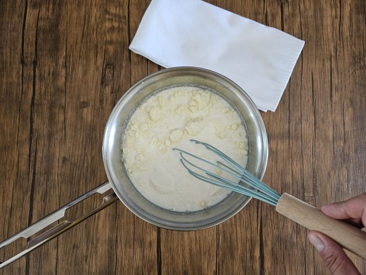 Uma panela contendo a mistura de leite, amido de milho, leite condensado, leite Ninho e creme de leite.