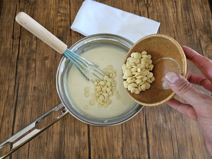 Uma panela contendo creme branco com chocolate branco.