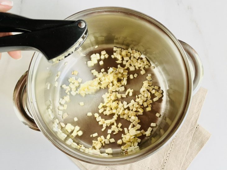 Uma panela com azeite, cebola e alho.