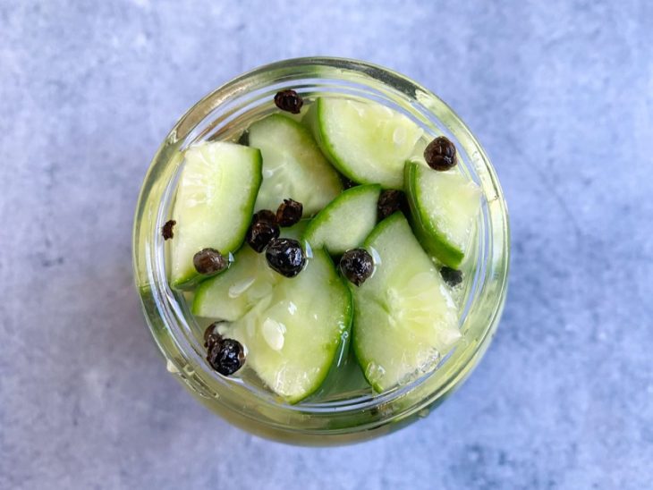 Um pote com o pepino, temperos e água fervente.