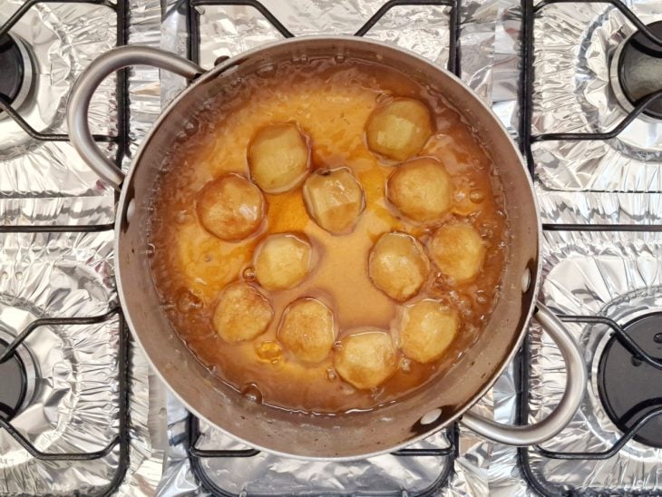 Pêssegos adicionados na calda de caramelo na panela.