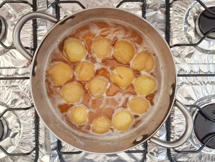 Pêssegos em processo de cozimento na calda de caramelo.