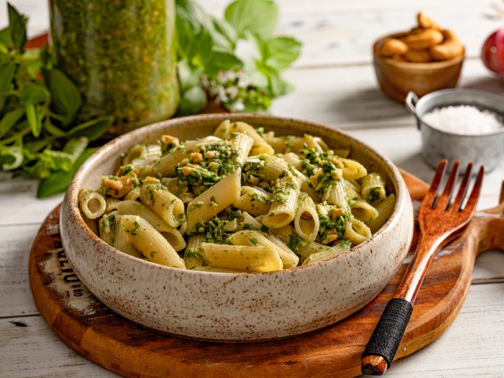 Prato redondo com penne ao pesto de manjericão.