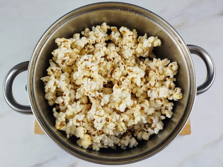 Pipoca adicionada a panela com a mistura de água com açúcar.