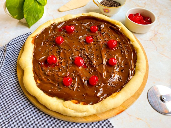 Pizza de chocolate decorada com cerejas e granulados pronta para consumo