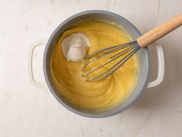 Uma panela com a polenta sendo misturada com creme de leite.