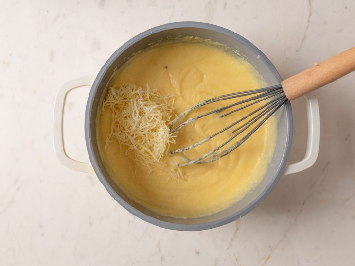 Panela com polenta e a adição de queijo parmesão.