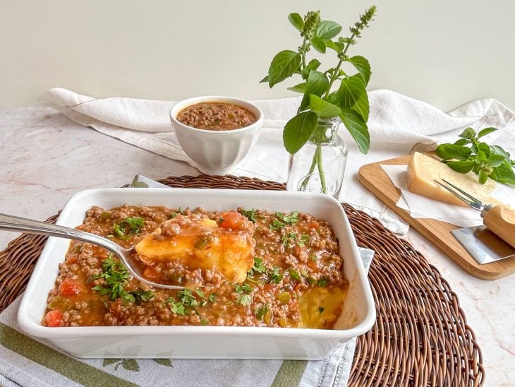 Polenta em uma travessa com a carne moída por cima, pronta para consumo.