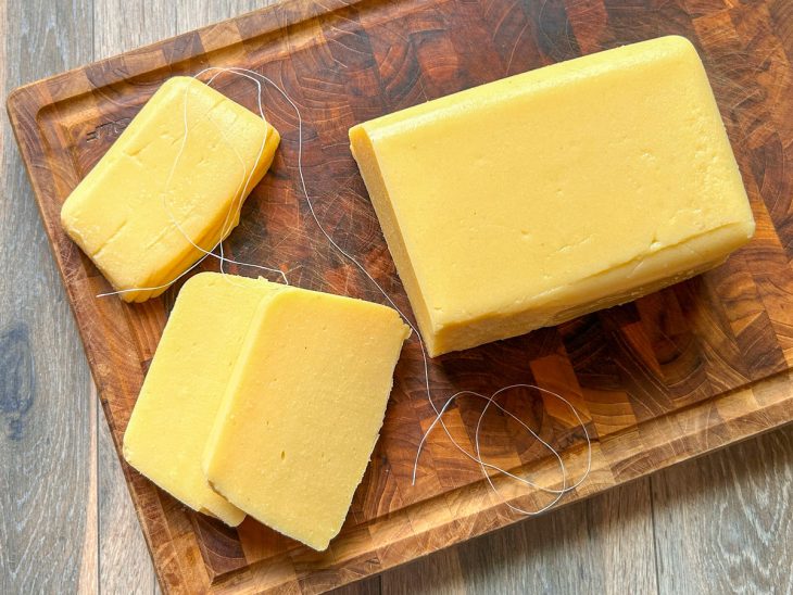 Polenta desenformada e com pedaços fatiados sobre uma tábua.