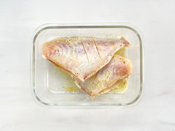 Um recipiente contendo dois peixes porquinhos temperados.