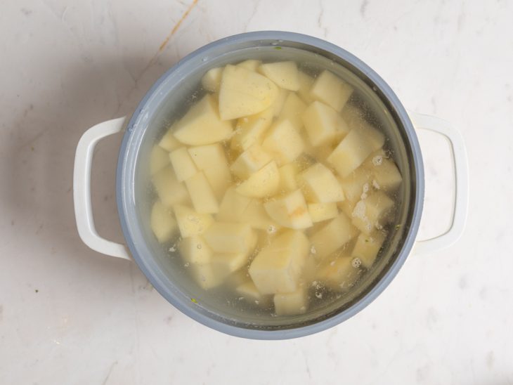 Batatas em cortes colocadas em uma panela com água e sal para cozinhar.