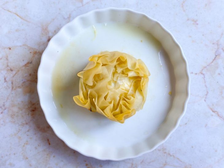 trouxa de queijo brie com massa filo em uma assadeira untada com manteiga.