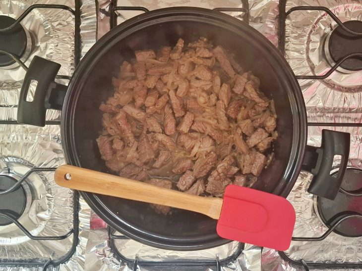 Pedaços de carne sendo dourados na panela.