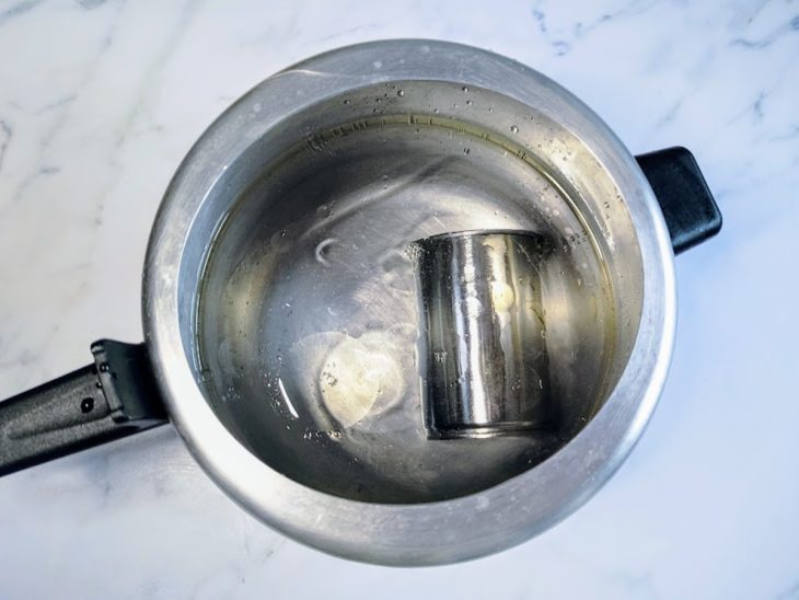 Uma panela de pressão contendo uma lata de leite condensado coberto com água com óleo.