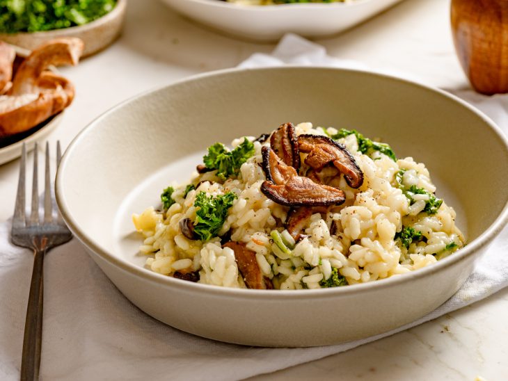 Um prato contendo risoto de cogumelos e kale.