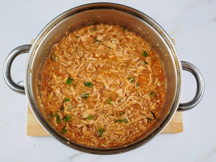 Frango desfiado, molho de tomate e água adicionados a panela.