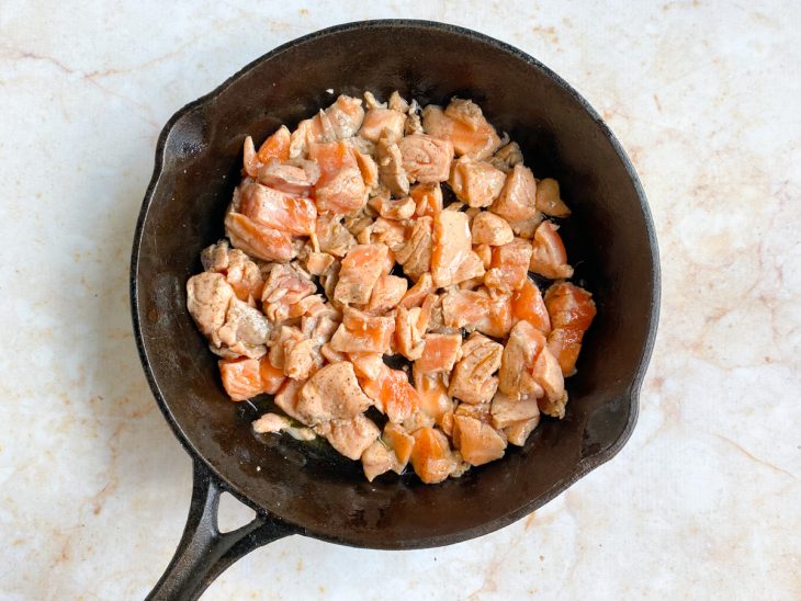 Uma frigideira com azeite e pedaços de salmão.