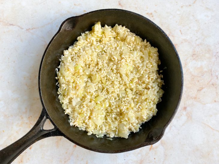 Uma frigideira com arroz, manteiga e cebola.