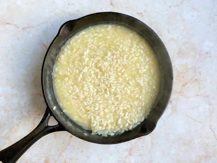 Uma frigideira com arroz cozinhando no caldo de legumes.