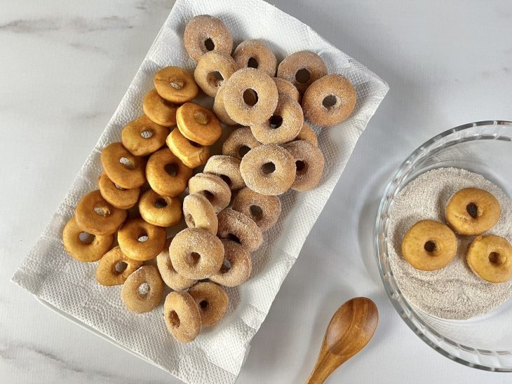 Um prato com rosquinhas fritas polvilhadas com açúcar.