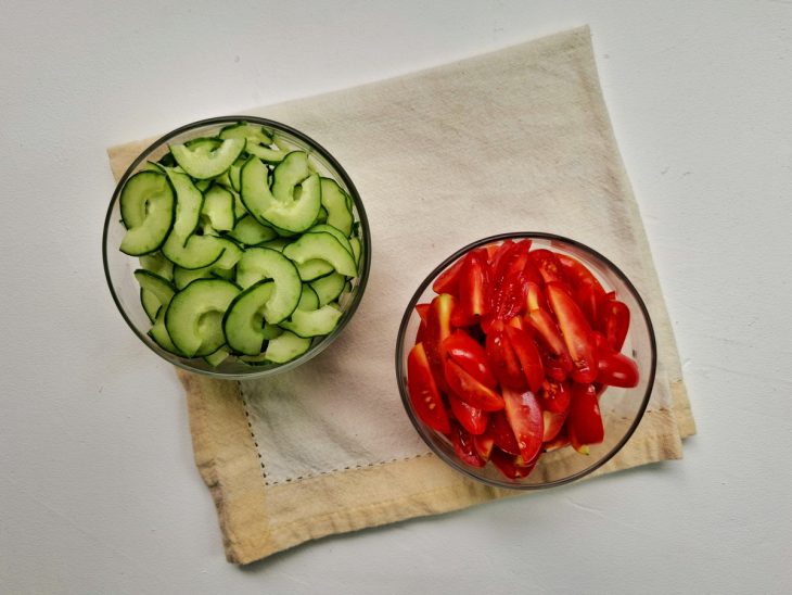 Tigelas com tomates-cerejas e pepino cortados.