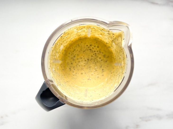 Um liquidificador com maracujá, creme de leite e suco de limão batidos.