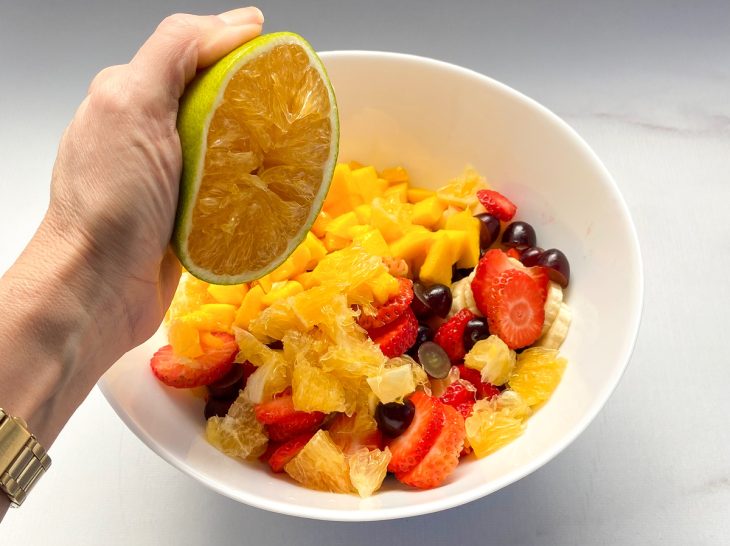 Um bowl com frutas cortadas e suco de laranja.