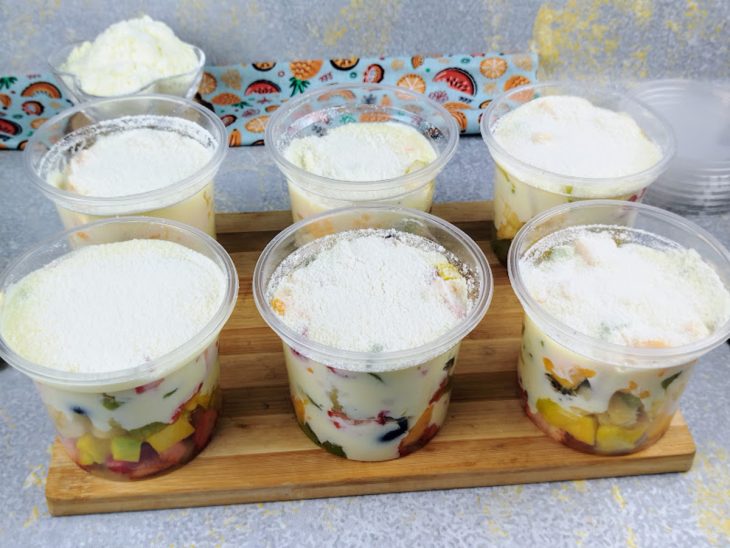 Potes finalizados com creme sobre as frutas e leite Ninho polvilhado.