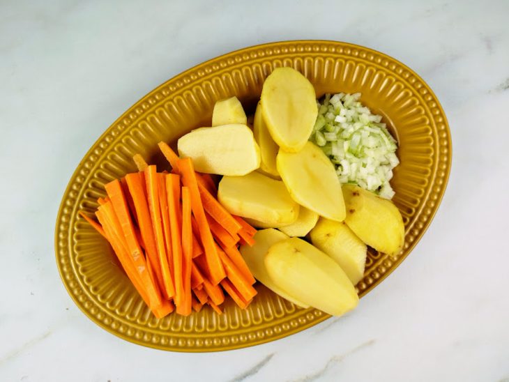 Cenoura, batata e cebola picada em um prato.