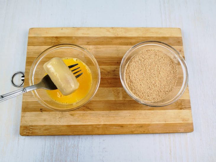 Salsicha para ser empanada em recipientes com ovo e farinha de rosca.