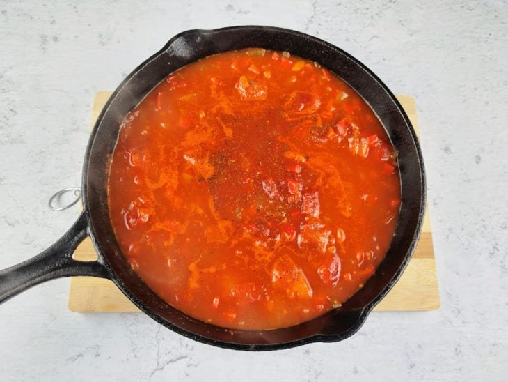 Pimentão, tomate pelado e temperos adicionados a frigideira.