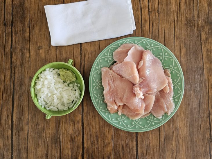 Recipientes com alho, cebola e frango picados.