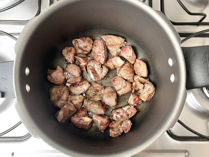 Uma panela de pressão selando pedaços de carnes.