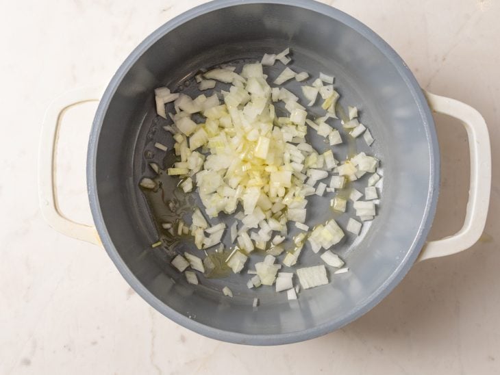 Cebola refogada com azeite em uma panela.