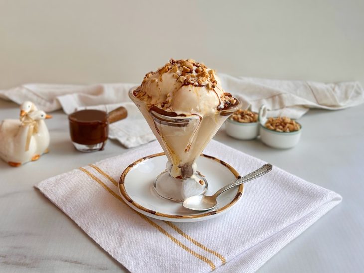 Bolas de sorvete com calda de chocolate em uma pequena taça de vidro.