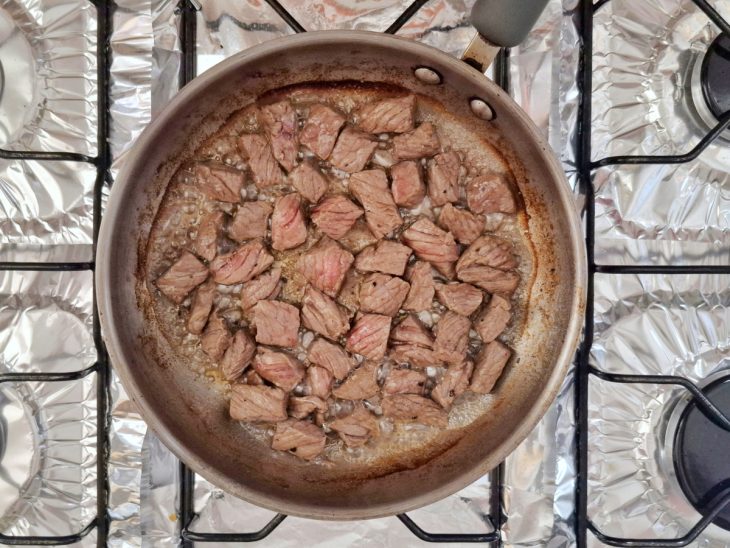 Carne em cubos em uma frigideira com azeite e manteiga.