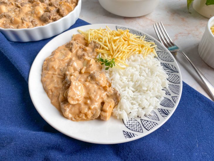 Prato redondo composto por arroz, porção de strogonoff de carne e batata palha.