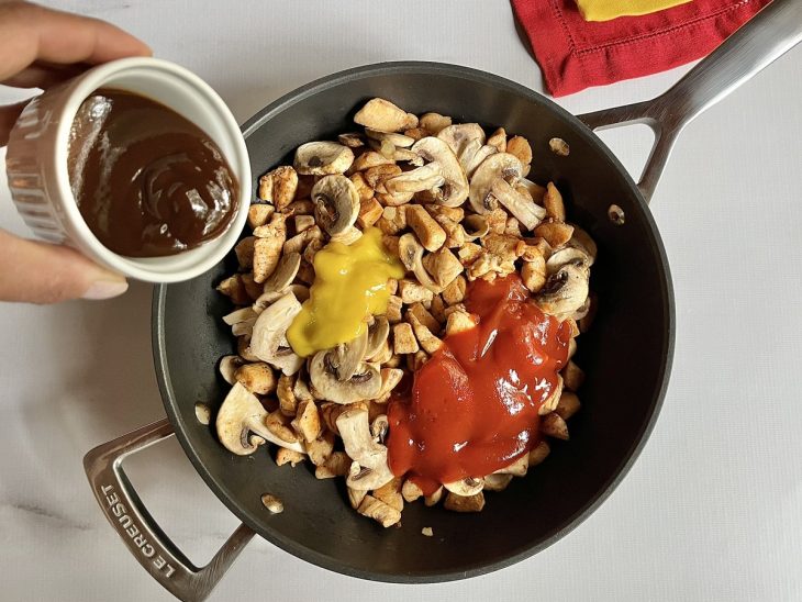 Uma panela com frango, temperos e molho cozinhando.