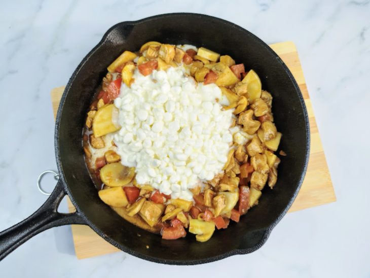 Uma frigideira refogando cebola picada, peito de frango cortado, tomate, champignon, mostarda, molho inglês, sal e queijo cottage.