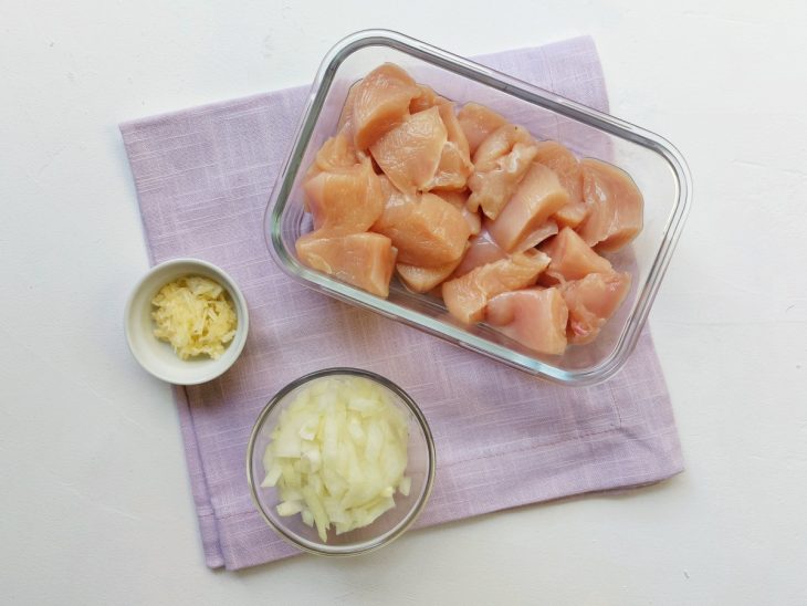 Recipientes com frango, alho e cebola picados.