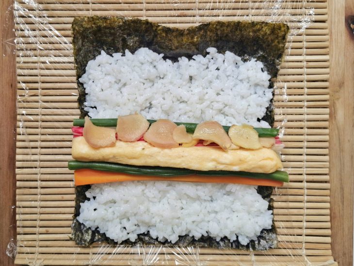 Recheio do sushi colocado no meio do arroz sobre o nori.