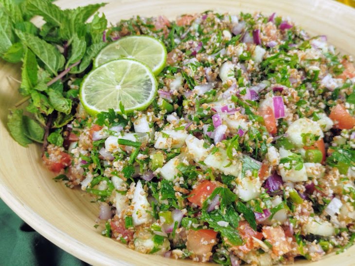 Sal, azeite, tempero sírio e caldo de limão espremido adicionados a tigela. Tabule original pronto para consumo.