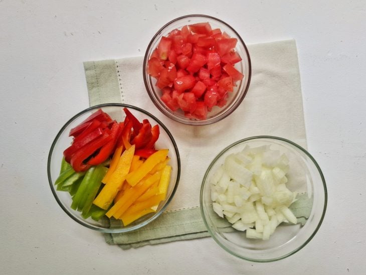 Recipientes com tomate, cebola e pimentões picados.